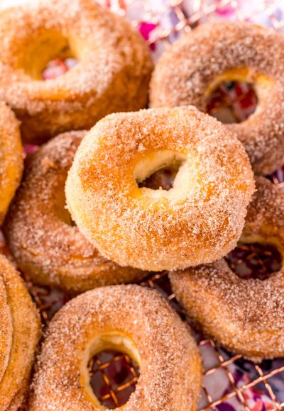 Air fryer cinnamon sugar donuts piled on a wire rack.