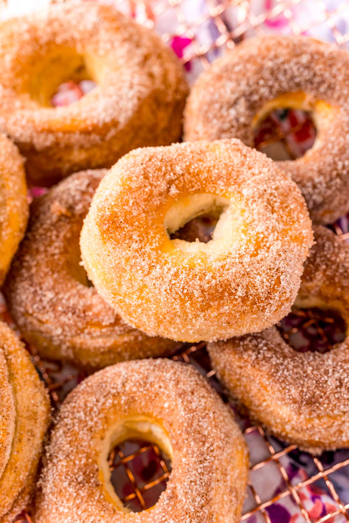 Air fryer cinnamon sugar donuts piled on a wire rack.