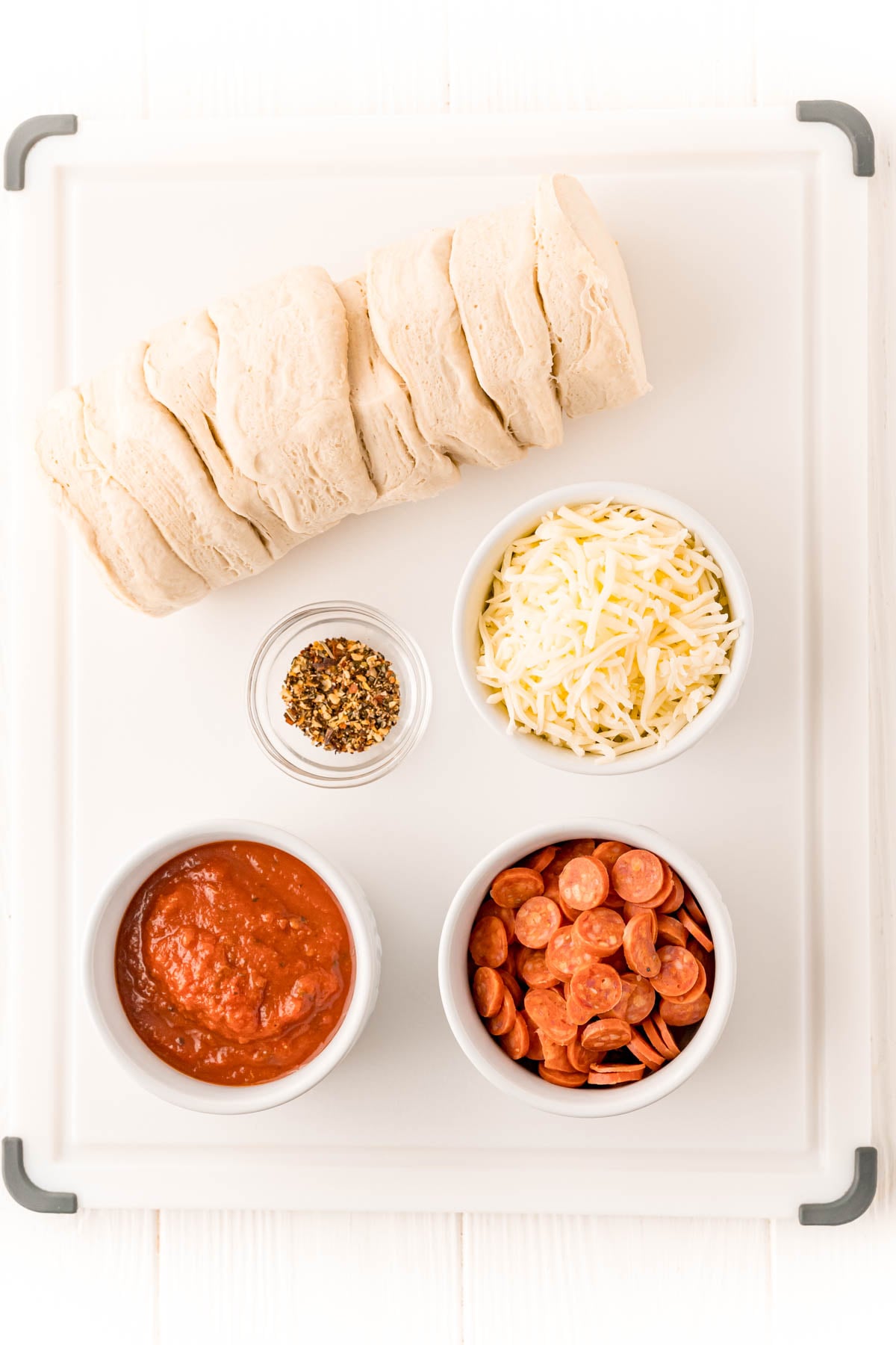 Overhead photo of ingredients to make air fryer pizzas on a white cutting board.