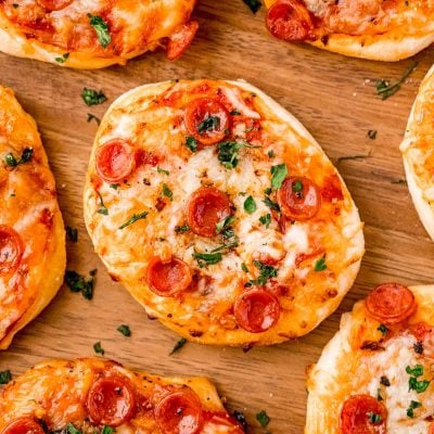 Close up photo of mini pizza on wood plate.