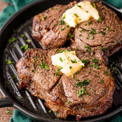 Two steaks on a black plate on a green napkin.