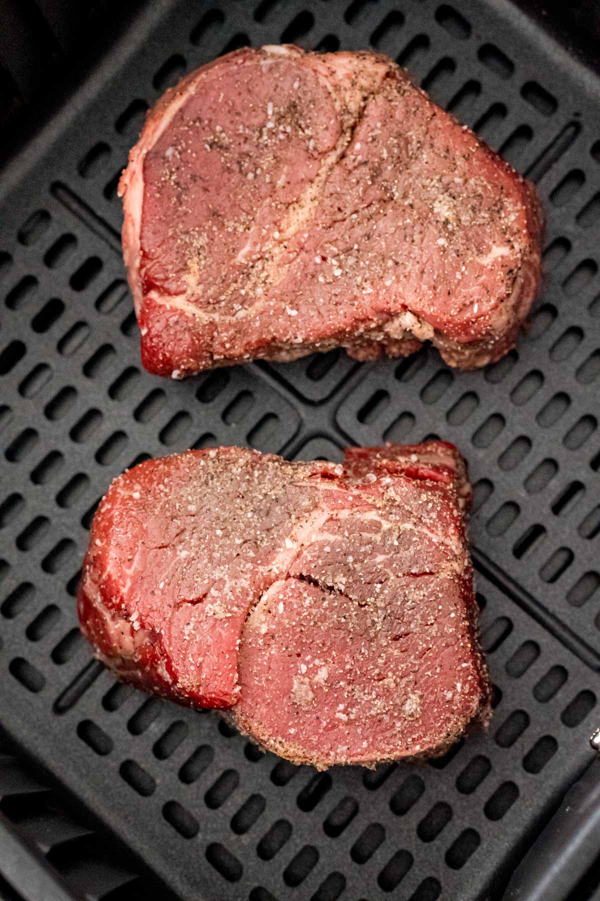 Steaks in air fryer ready to be cooked.