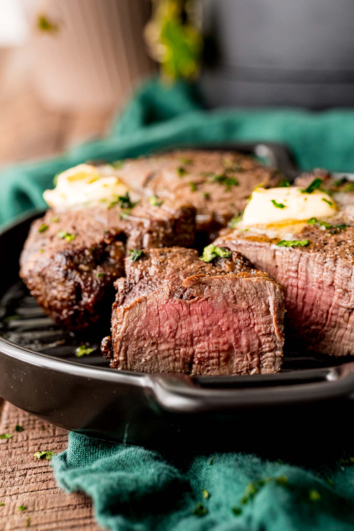 Close up photo of a piece of steak sliced showing a pink center with the rest of the steak behind it on the plate.