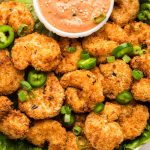 Overhead photo of a bowl filled with crispy air fryer shrimp with a dipping sauce.