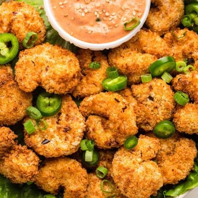 Overhead photo of a bowl filled with crispy air fryer shrimp with a dipping sauce.