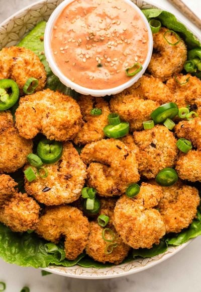 Overhead photo of a bowl filled with crispy air fryer shrimp with a dipping sauce.