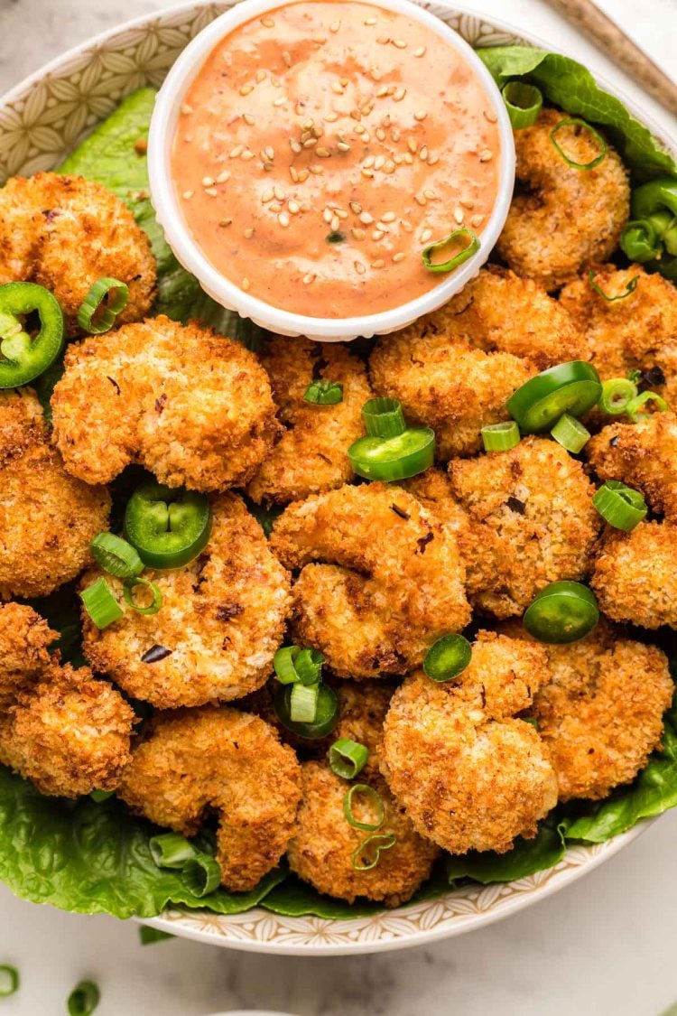 Overhead photo of a bowl filled with crispy air fryer shrimp with a dipping sauce.