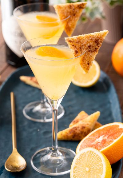 A close up photo of a breakfast martini garnished with cinnamon toast on a blue plate.