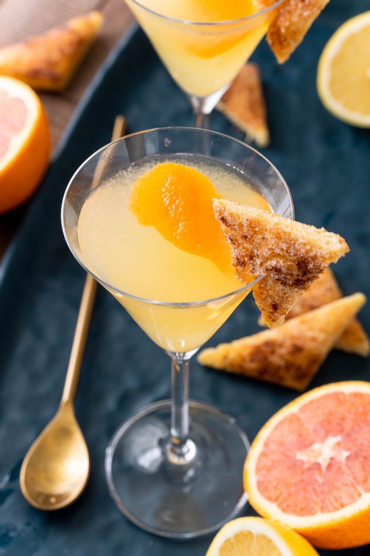 Close up photo of a breakfast martini garnished with cinnamon toast on a blue platter.