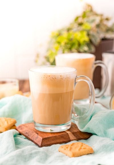 A breve latte sitting on a wooden coaster on a blue napkin.