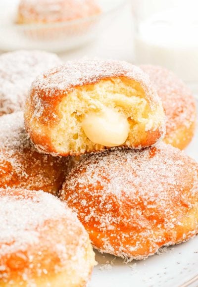 Close up photo of brioche donuts, the top on has a bite missing from it showing vanilla cream inside.