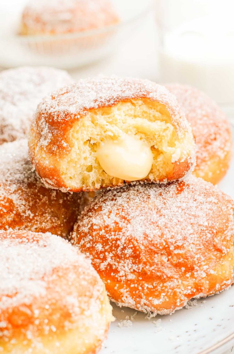 Close up photo of brioche donuts, the top on has a bite missing from it showing vanilla cream inside.