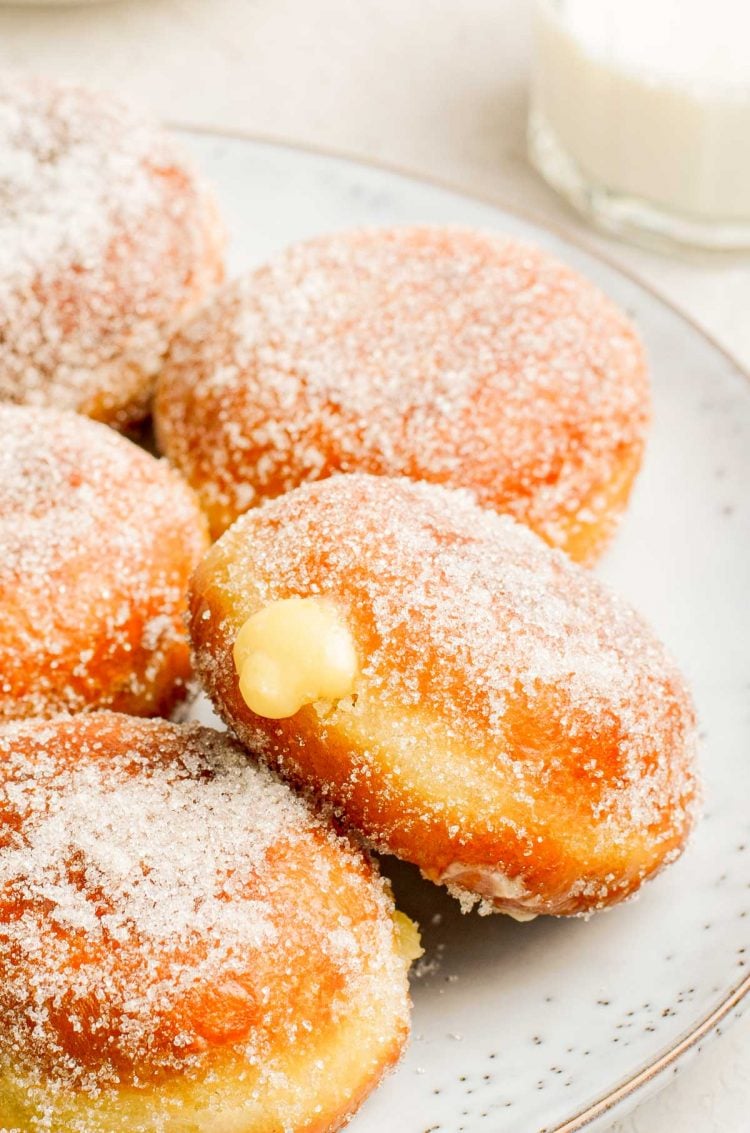 Close up photo of brioche donuts filled with vanilla pastry cream on a plate.