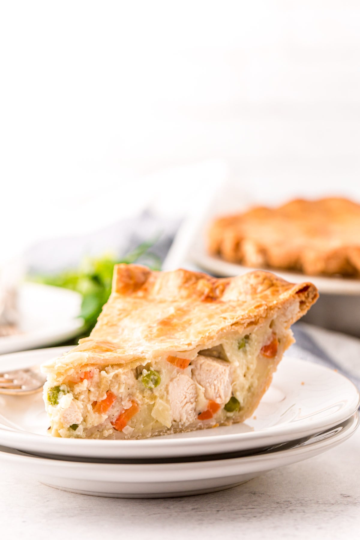 Close up photo of a slice of chicken pot pie on a white plate.
