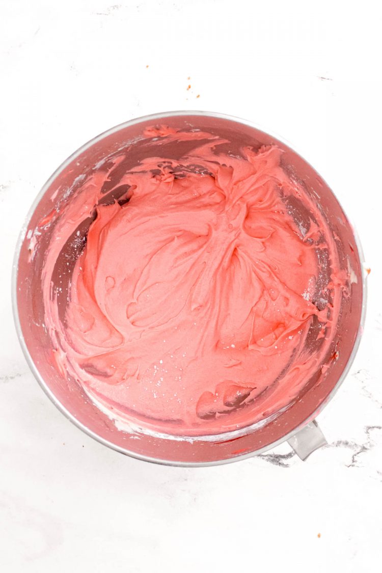 Overhead photo of strawberry frosting in a stainless steel mixing bowl.