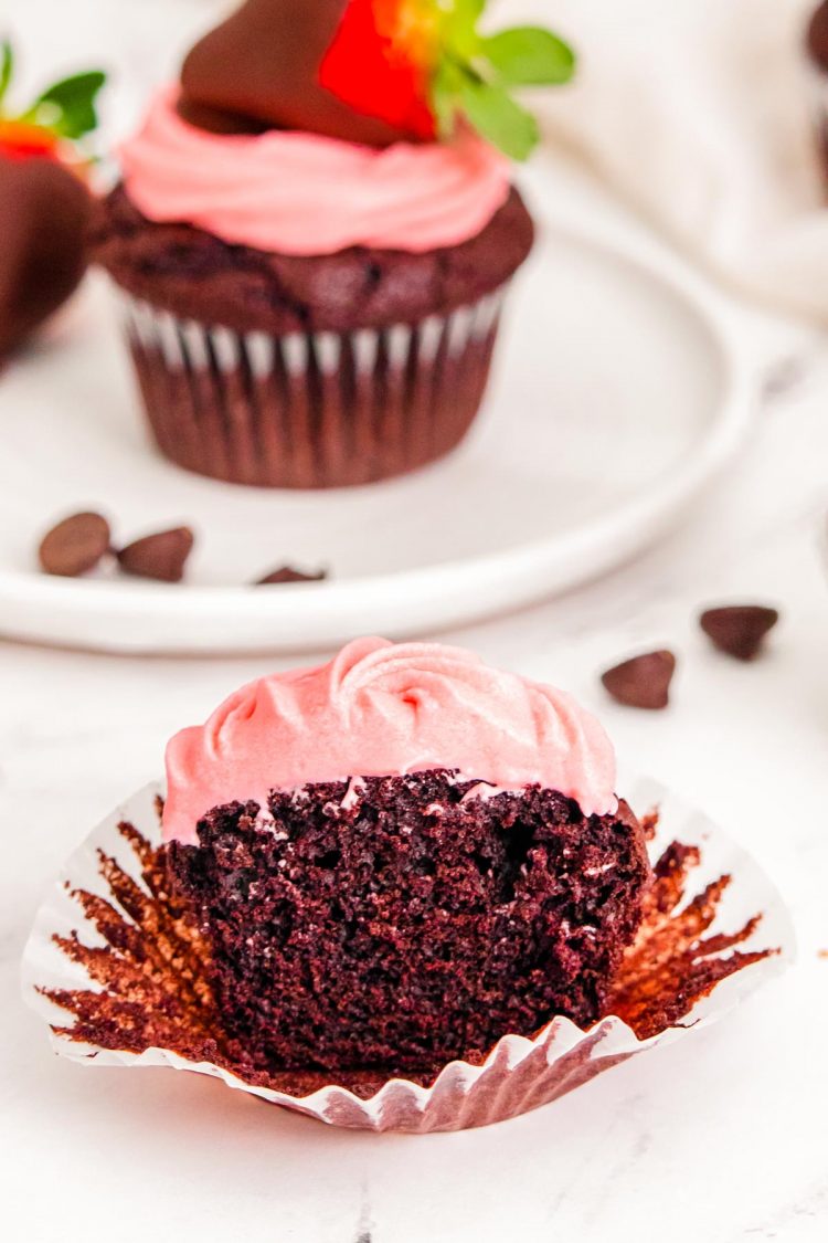 Close up photo of a Strawberry chocolate cupcakes cut in half on a white table.