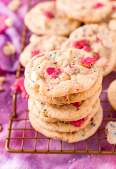 Close up photo of a stack of circus animal sugar cookies on a copper wire rack on a purple napkin.