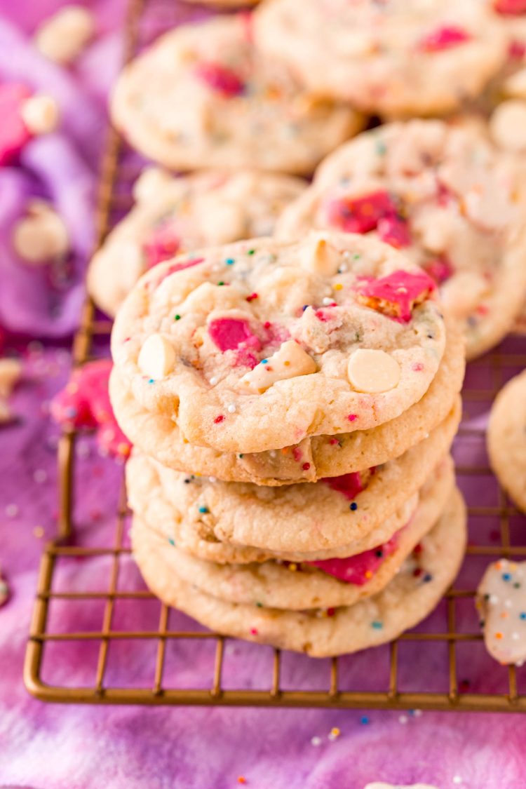 Close up photo of a stack of circus animal sugar cookies on a copper wire rack on a purple napkin.