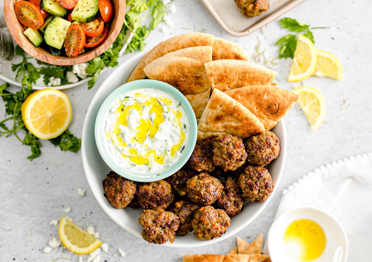 Overhead photo of Greek meatballs with tzatziki sauce and pita bread.