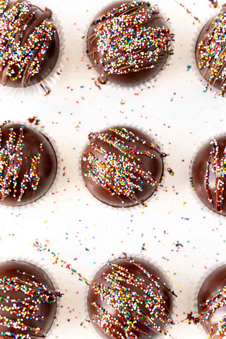 Overhead photo of 9 hot chocolate bombs topped with rainbow sprinkles.