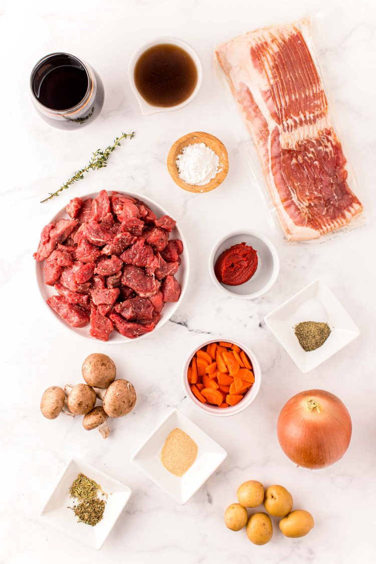 Overhead photo of ingredients to make beef bourguignon in an instant pot on a white table.