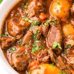 Close up photo of beef bourguignon in a white bowl.