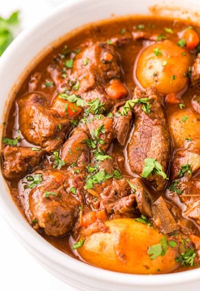 Close up photo of beef bourguignon in a white bowl.