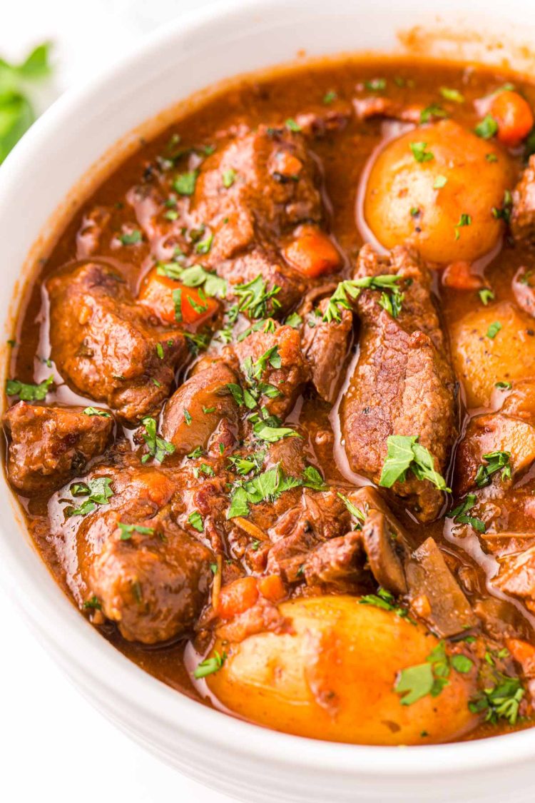 Close up photo of beef bourguignon in a white bowl.