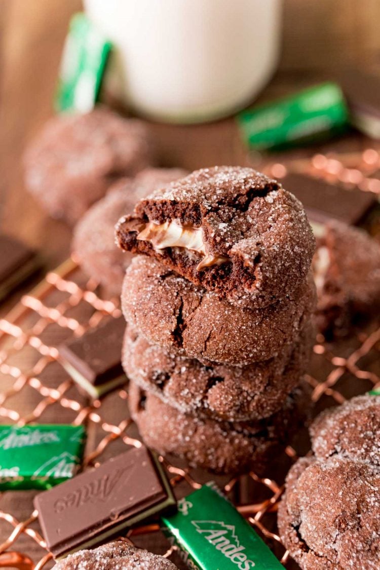 A stack of chocolate mint cookies on a cooling rack. The top on has a bite taken out of it.