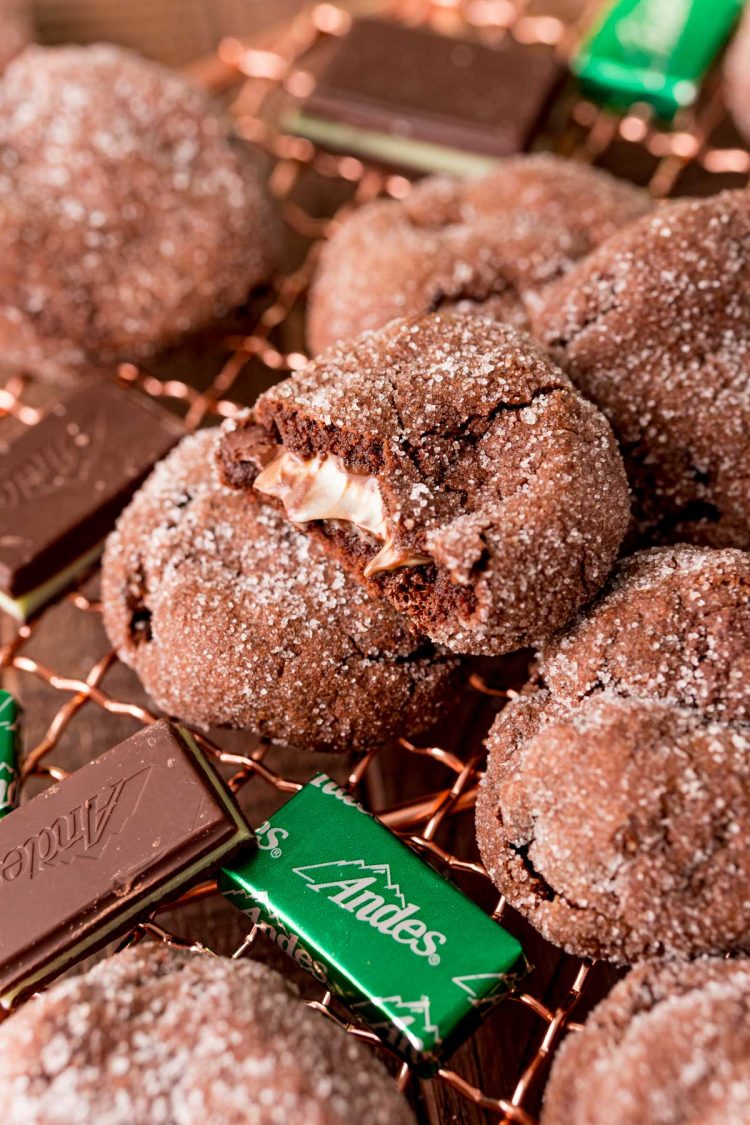 Close up photo of mint chocolate cookies with Andes mints on a copper wire rack.