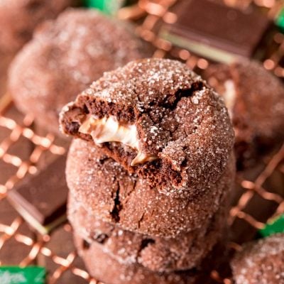 A stack of chocolate mint cookies on a cooling rack. The top on has a bite taken out of it.