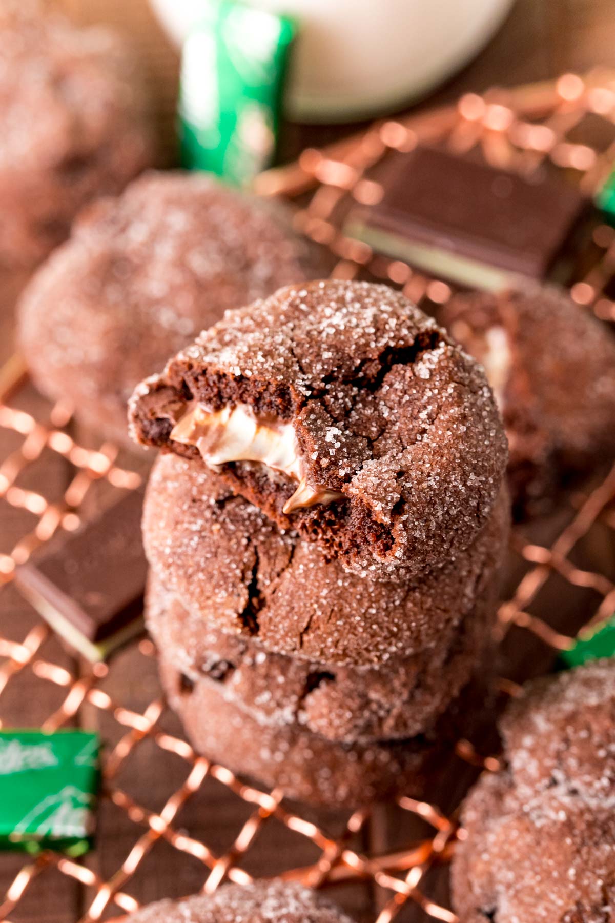 A stack of chocolate mint cookies on a cooling rack. The top on has a bite taken out of it.
