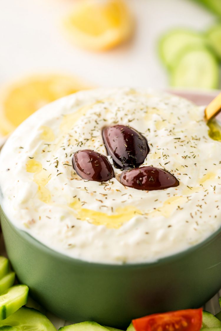 Close up photo of a green bowl with tzatziki sauce in it.