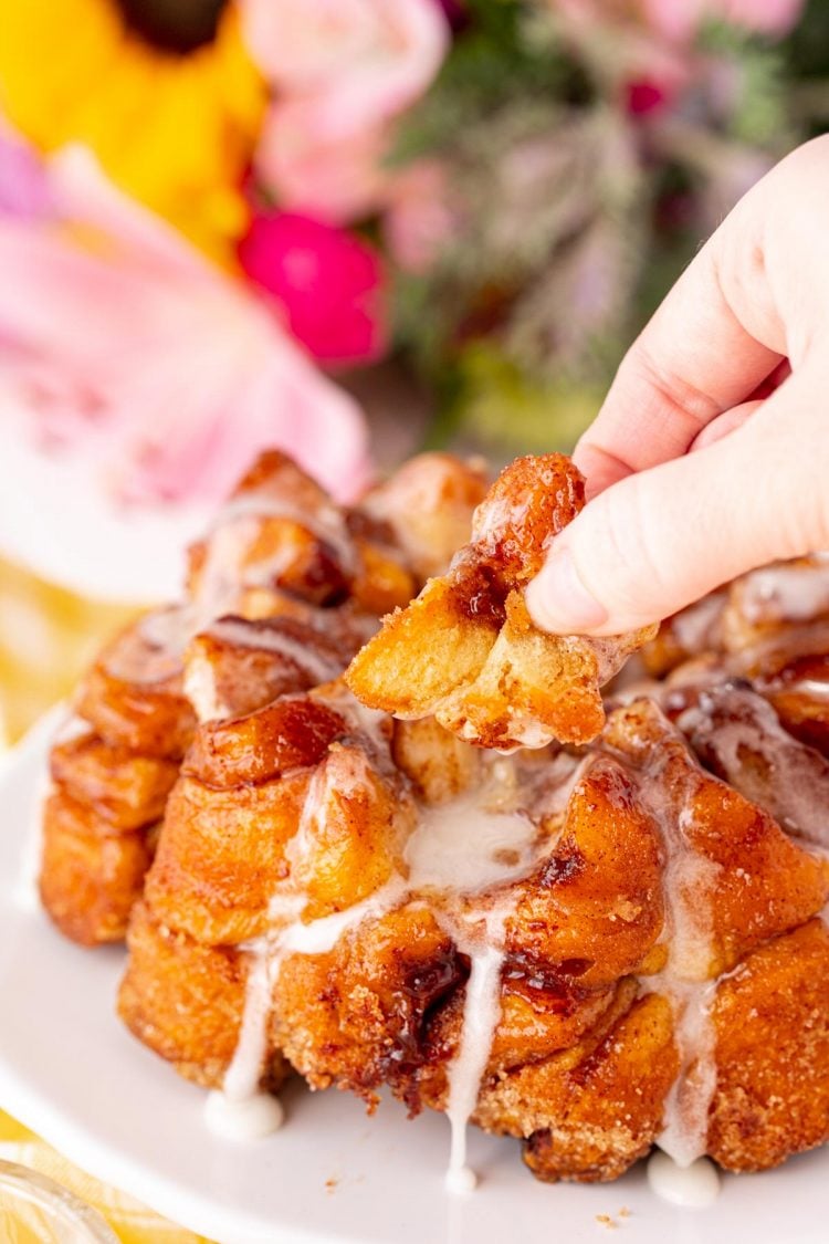 Close up photo of a woman's hand pulling a piece of monkey bread from the loaf.