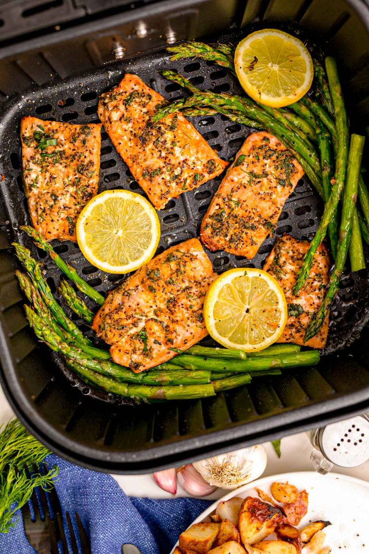 Overhead photo of salmon being cooked in an air fryer with asparagus.