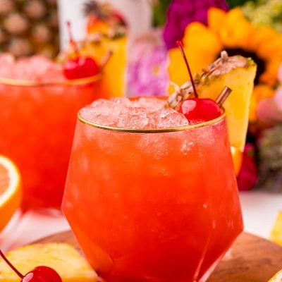 Close up photo of a bahama mama cocktail garnished with a maraschino cherry and pineapple wedge.
