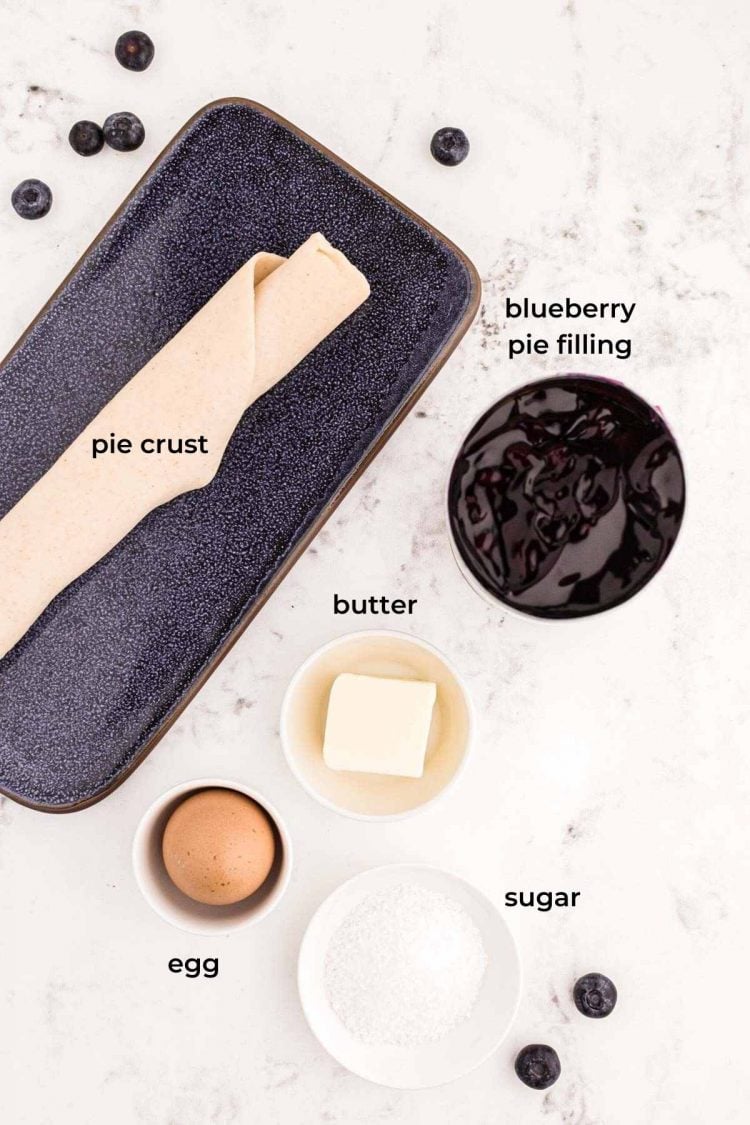 Ingredients to make blueberry hand pies on a marble counter.