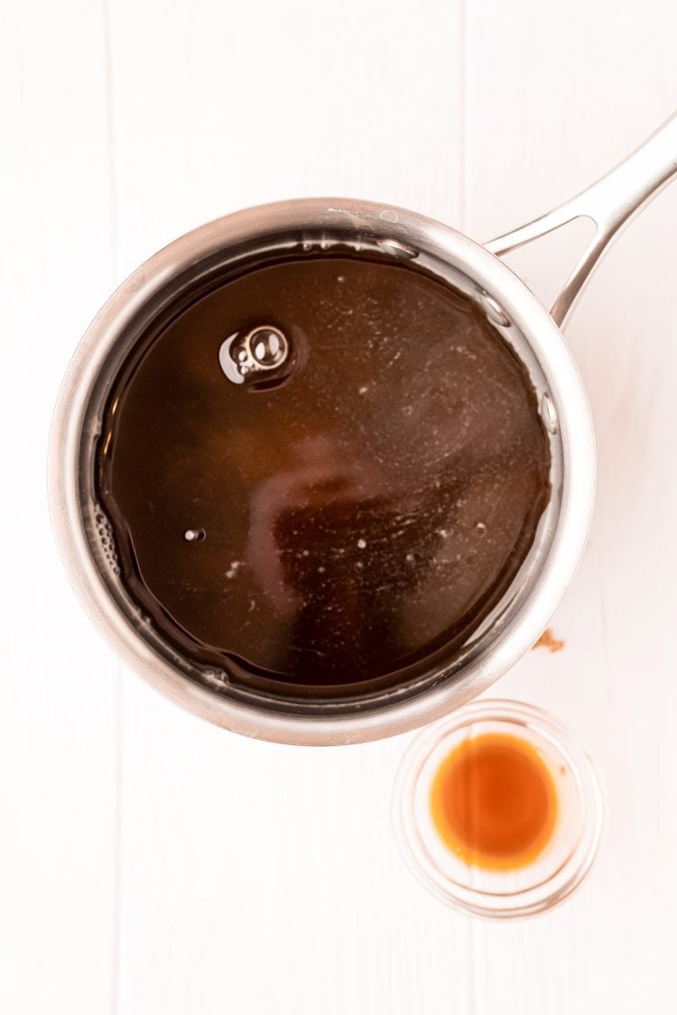 Overhead photo of a small saucepan of brown sugar simple syrup with a small bowl of vanilla extract next to it.