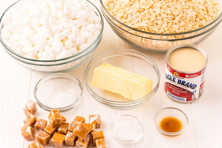 Ingredients to make salted caramel rice krispie treats on a white wood table.
