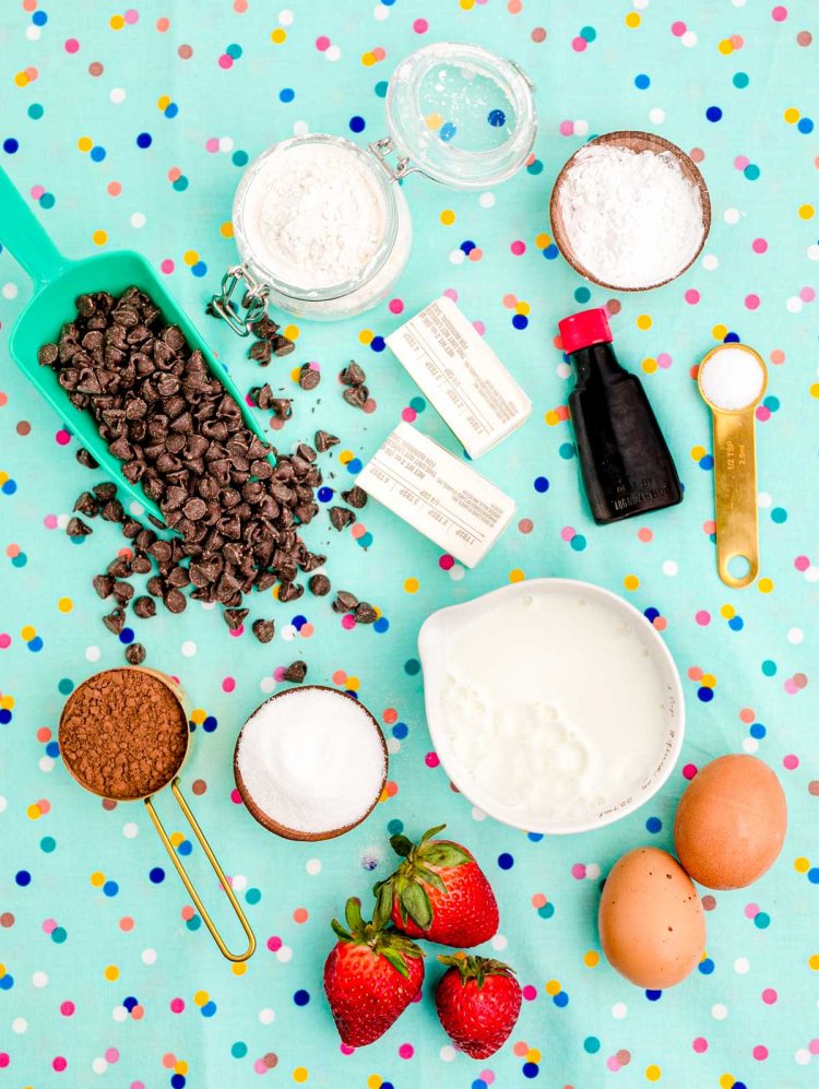 Overhead photo of ingredients used to make chocolate waffles on a teal surface.