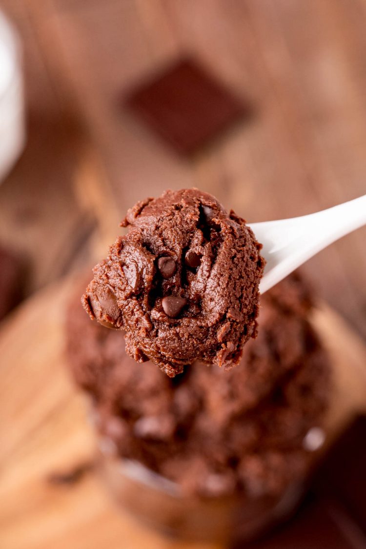 A spoon with edible brownie batter on it being held close to the camera.