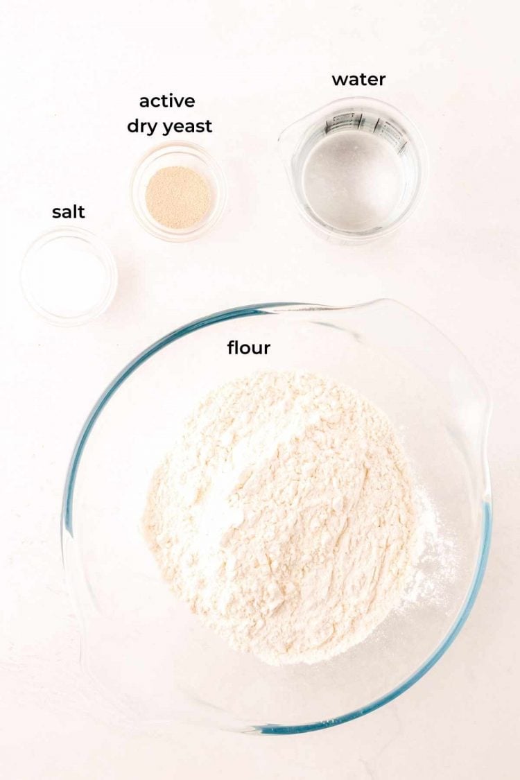 Overhead photo of ingredients to make a French baguette on a white table.