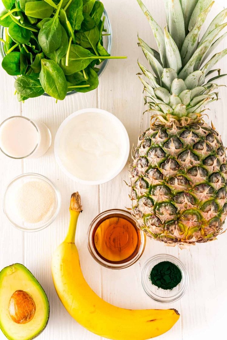 Ingredients to make a green smoothie on a white table.