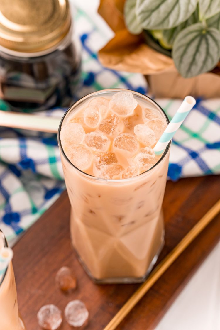 Close up photo of a cookie butter latte in a glass with a blue and white napkin in the background.