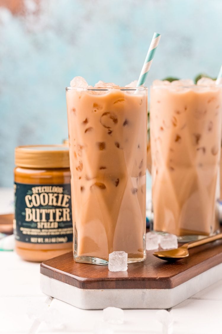 Straight on photo of two glasses filled with iced cookie butter lattes and a jar of cookie butter next to it.