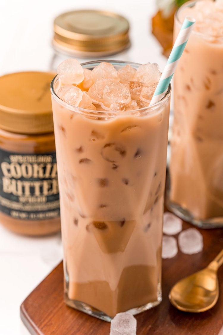 Close up photo of an iced cookie butter latte with a blue and white paper straw.