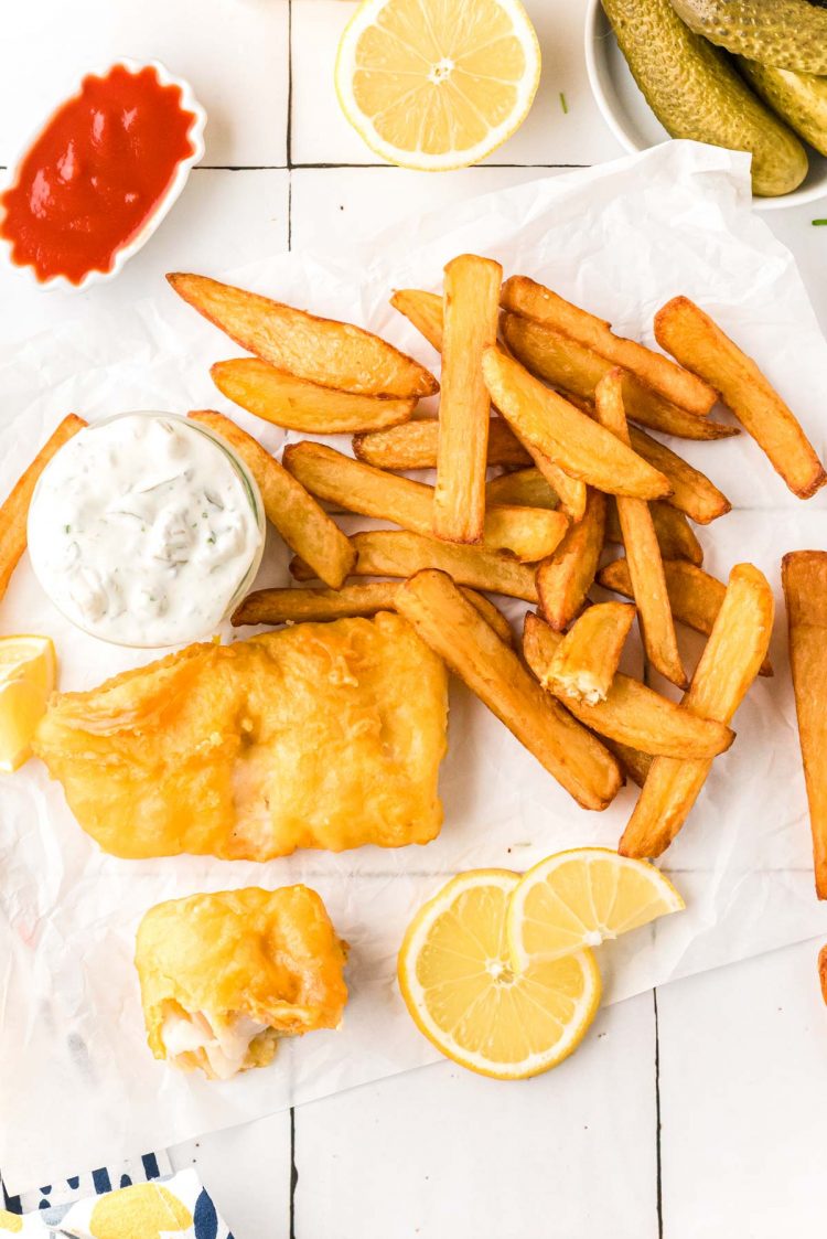 Overhead photo of fish and chips on a white table.