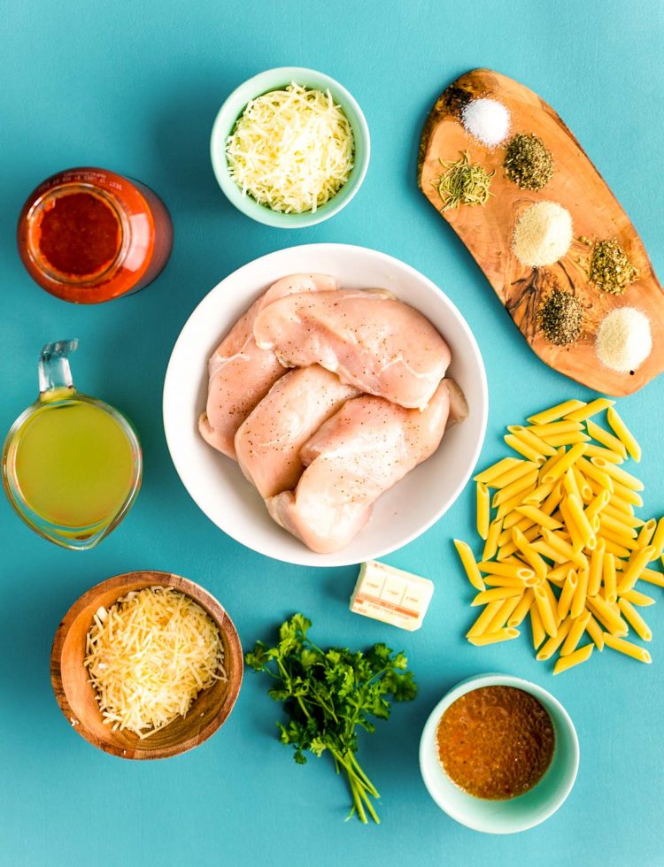 Overhead photo of ingredients prepped to make chicken parmesan pasta in an instant pot on a teal background.