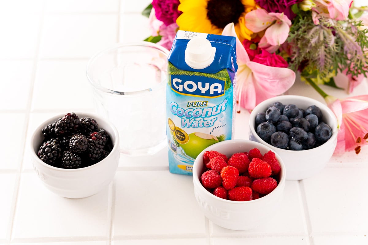 Ingredients to make Nature's Cereal on a white table with flowers in the background.