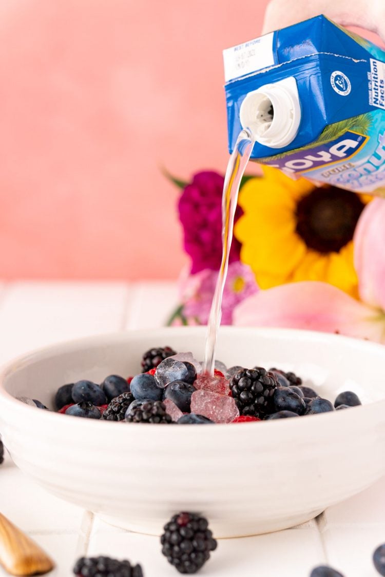 Coconut water being poured into a bowl with fruit to make Nature's Cereal.